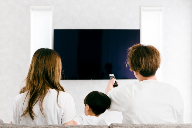 家族でテレビの大画面を見るイメージ